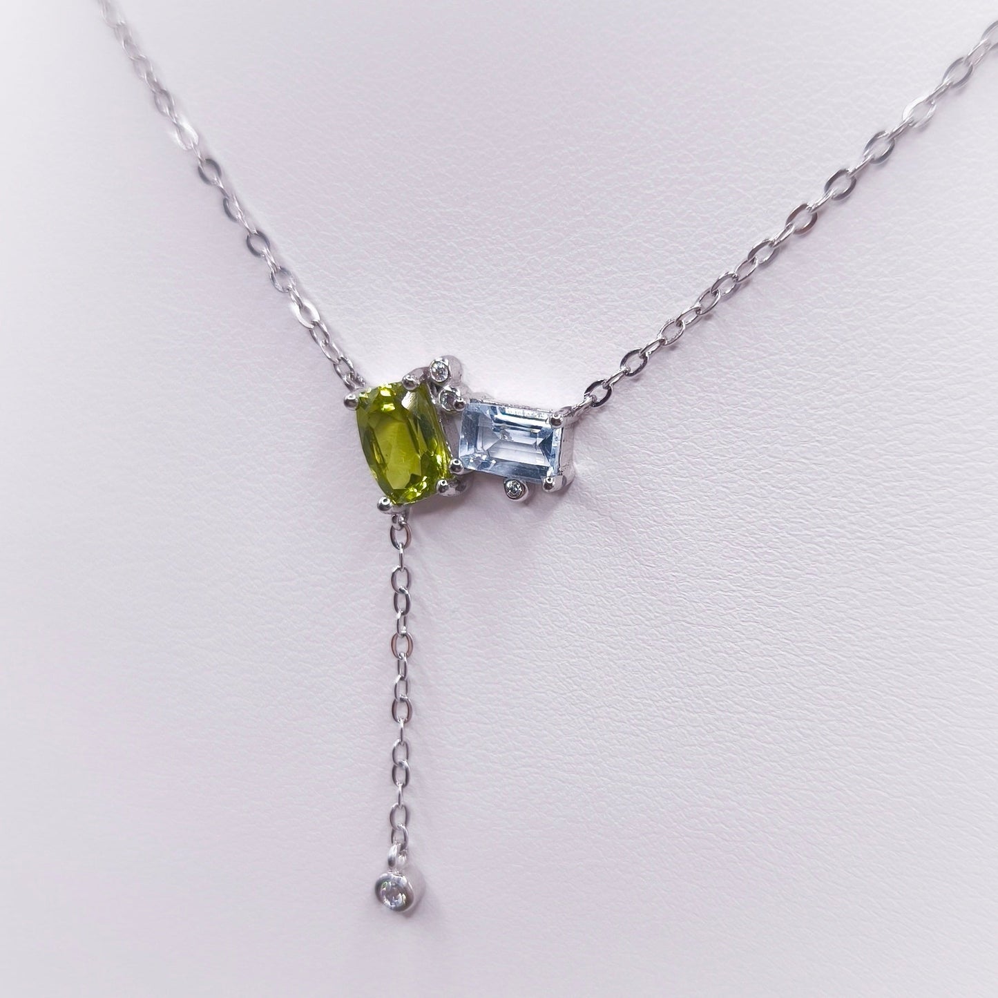 Sterling silver toi et moi necklace with oval peridot and emerald-cut Swiss blue topaz gemstones, 7x5 mm